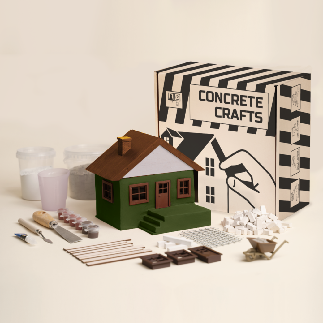 Cast concrete miniature house in green with model tools and micro bricks – a realistic diorama build ready for a shelf display