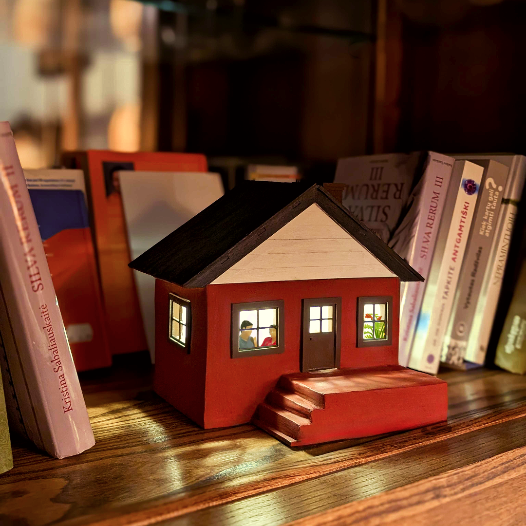 miniature house is standing on a bookshelf