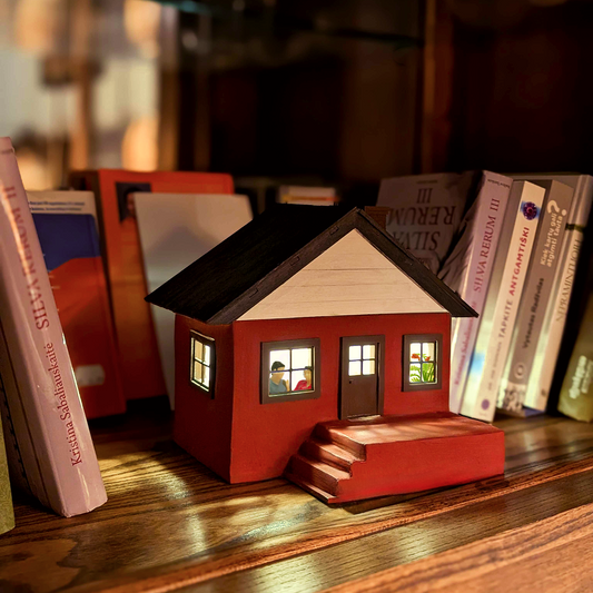 miniature house is standing on a bookshelf