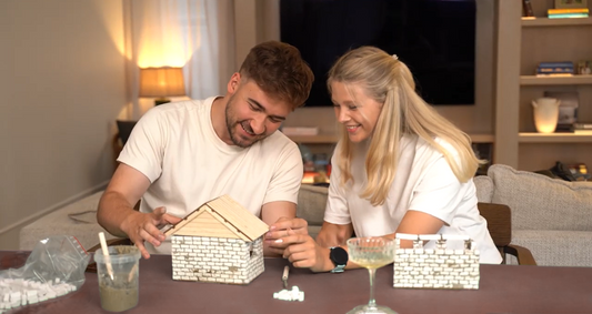 Two people working on a DIY miniature house made out of concrete and other real materials
