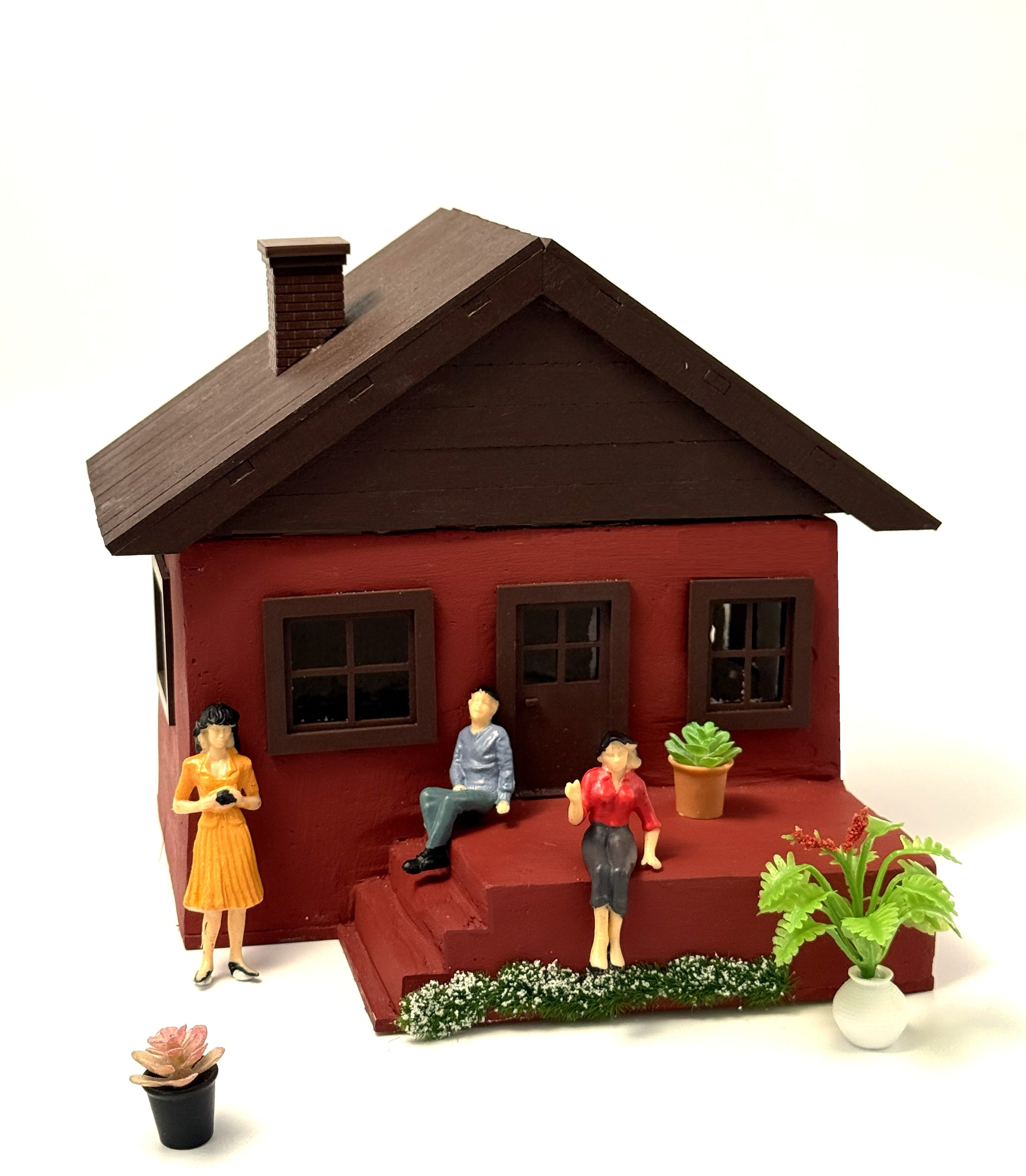 Miniature concrete house decorated with small plant pots and family figures